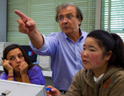 two students and one professor in class, the professor is pointing.